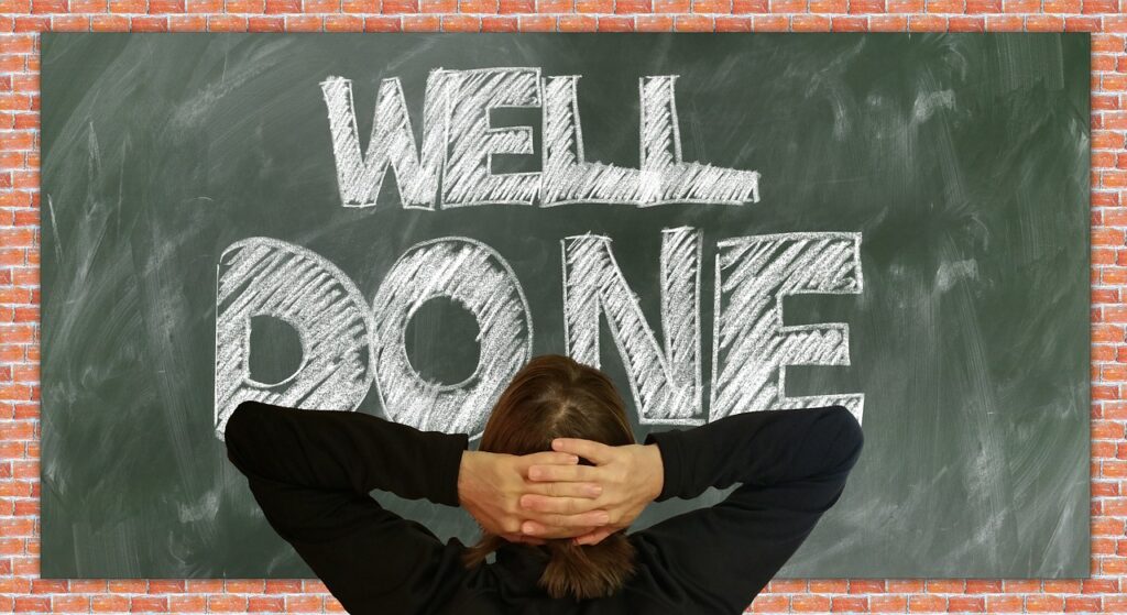 Woman staring at a whiteboard with hands behind head. Whiteboard say "Well done".